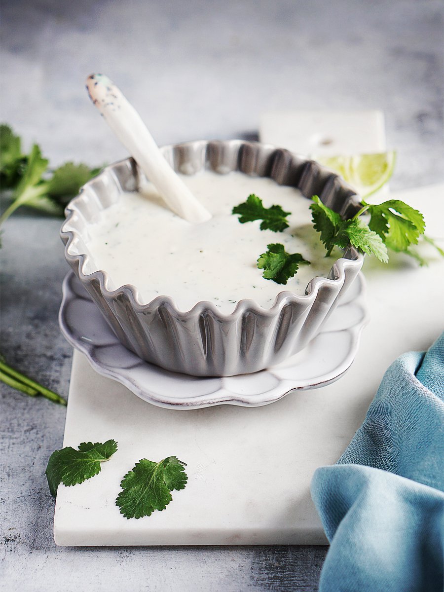 A gray bowl with crema garnished with cilantro
