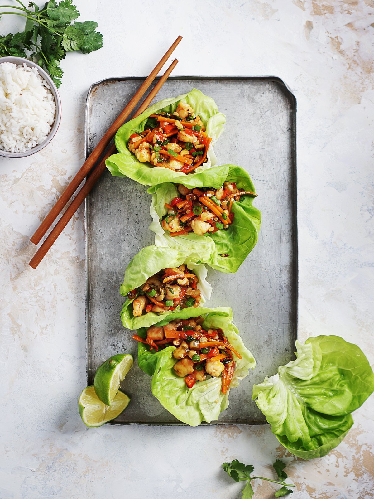 Four lettuce wraps on top of a metal tray.