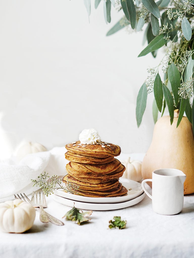 A stack of Protein Pumpkin Pancakes set on a table with a white tablecloth