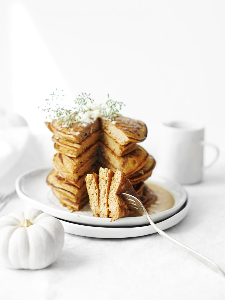 A stack of Protein Pumpkin Pancakes set on a table with a white tablecloth
