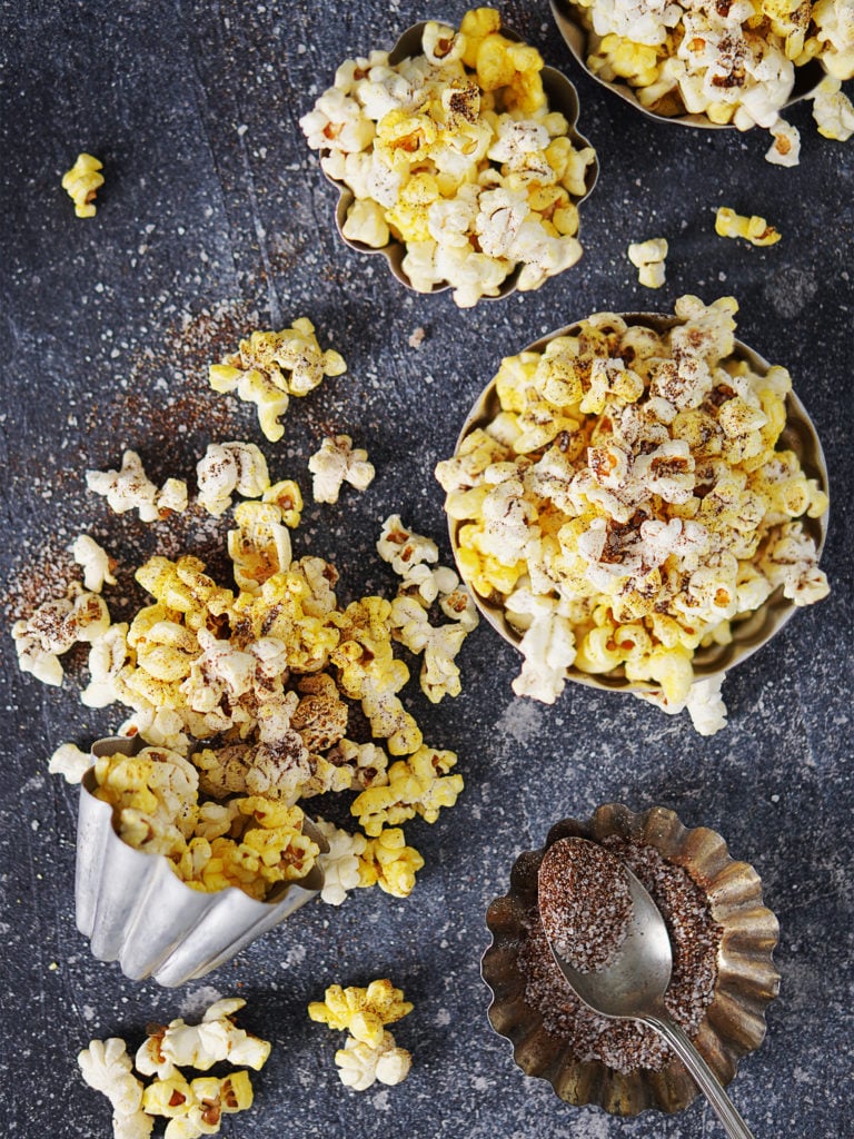 Palomitas (popcorn) scattered on a dark board with spices on a spoon