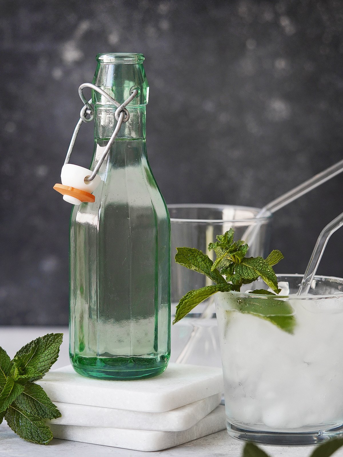 A green bottle with clear simply syrup. with mint as garnish