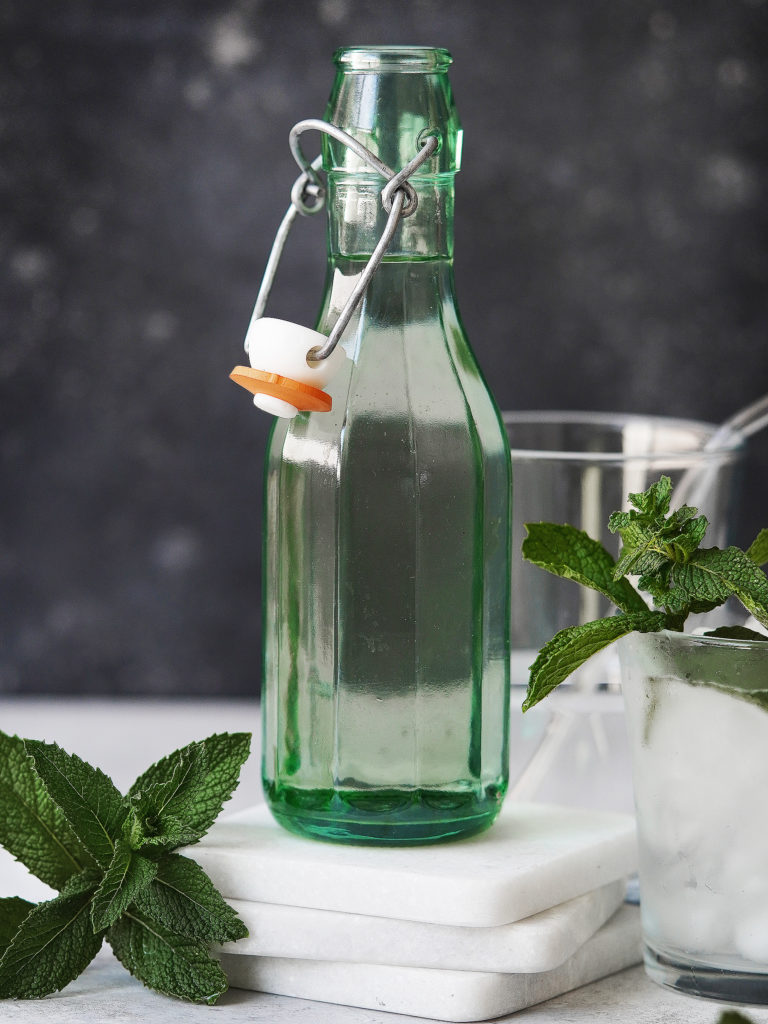 A green bottle with clear with mint as garnish