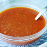 Consome sauce in a small bowl with a ladle in it.