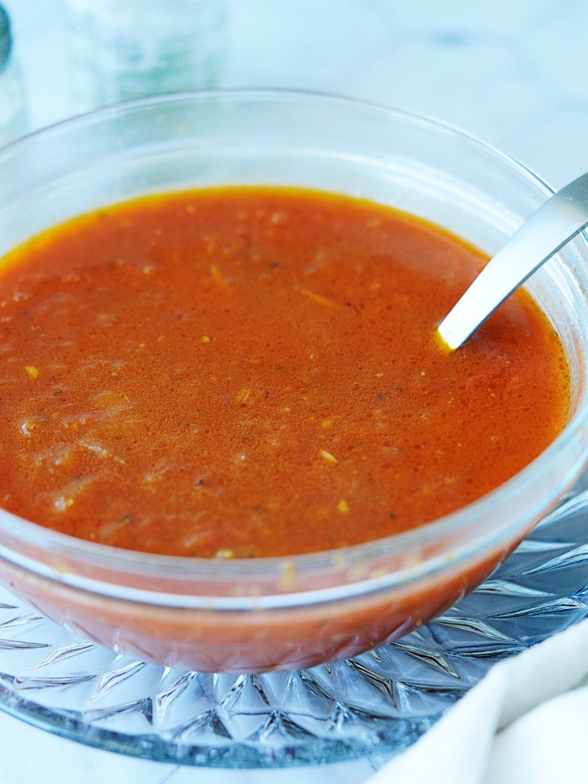 Consome sauce in a small bowl with a ladle in it.