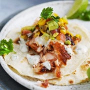 One blackened salmon taco placed on a gray plate topped with corn salsa