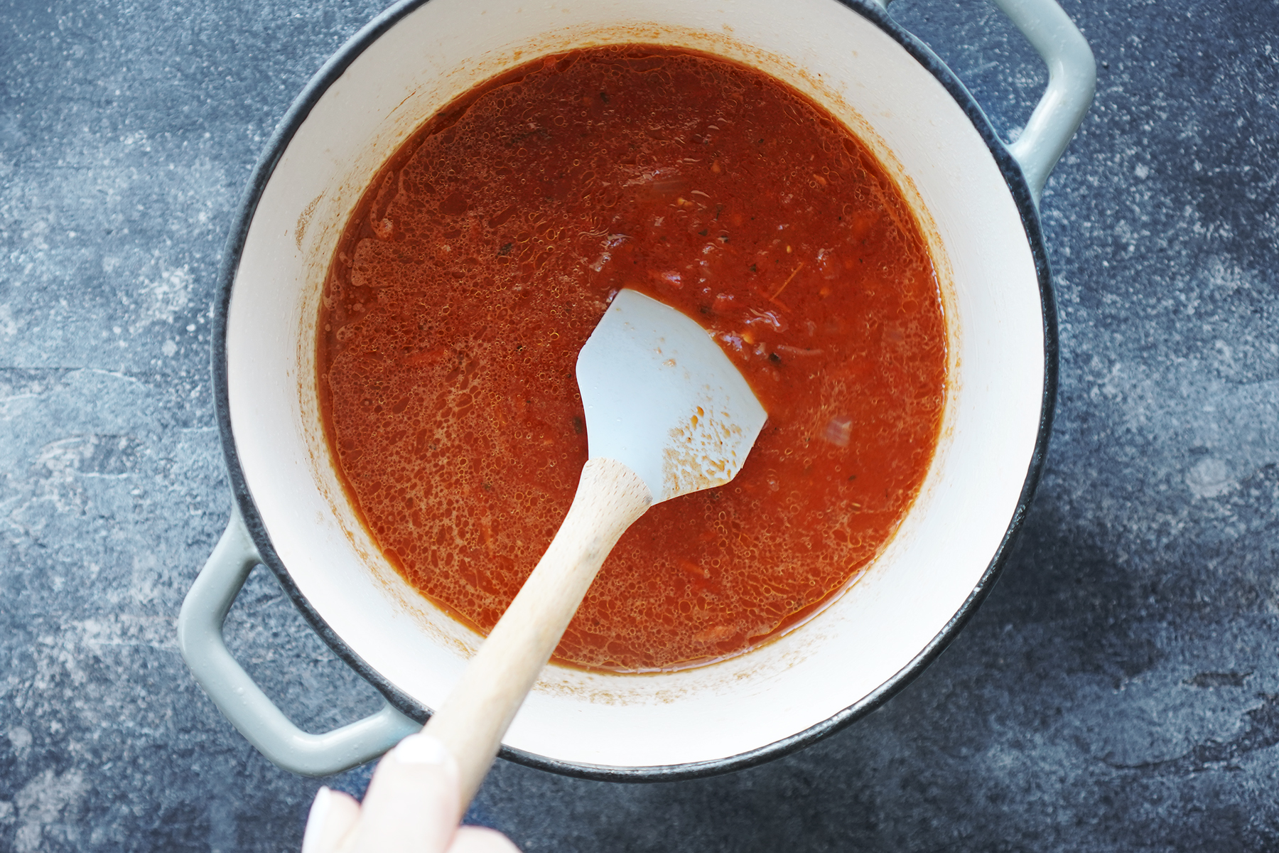 Tomato sauce in a saucepan placed on a blue background