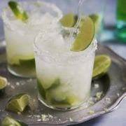 Caipirinha served with crushed ice and limes scattered around.