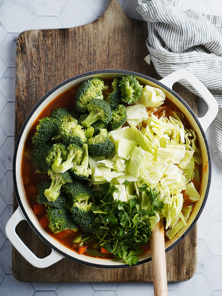Adding the broccoli, cilantro and cabbage to the pot
