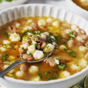 A white bowl with hominy and bean soup