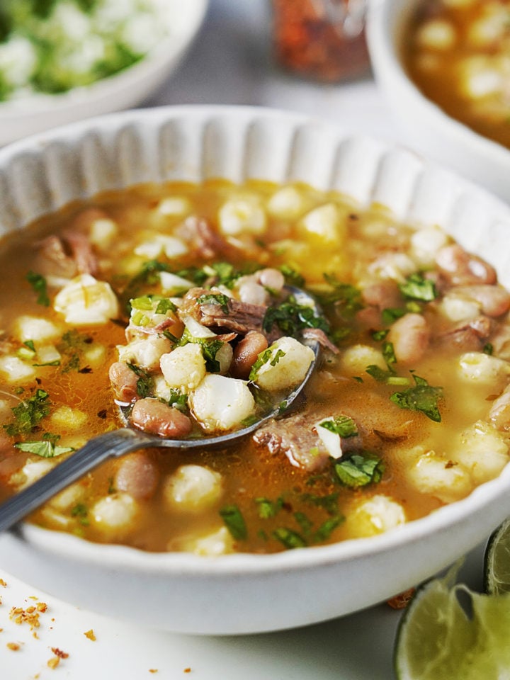 A white bowl with hominy and bean soup