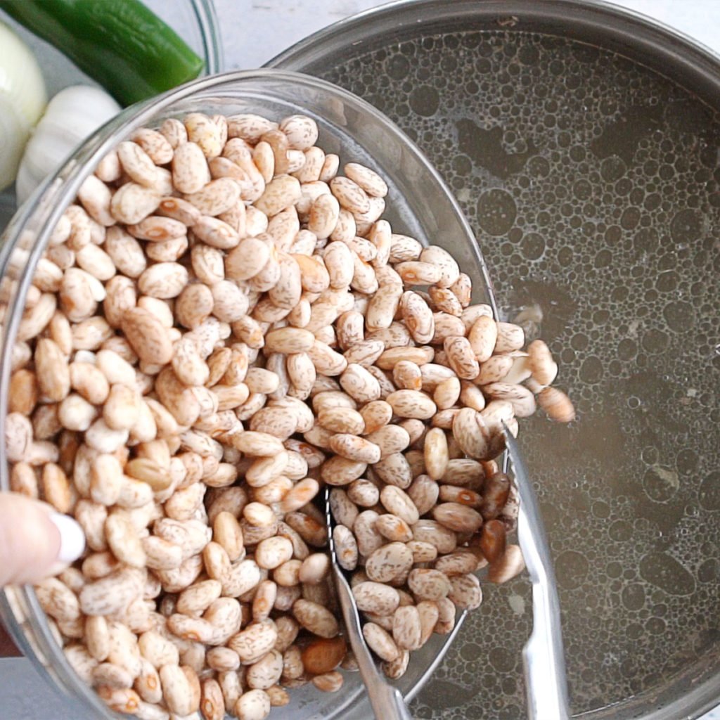 Adding pinto beans into a big pot with beef broth
