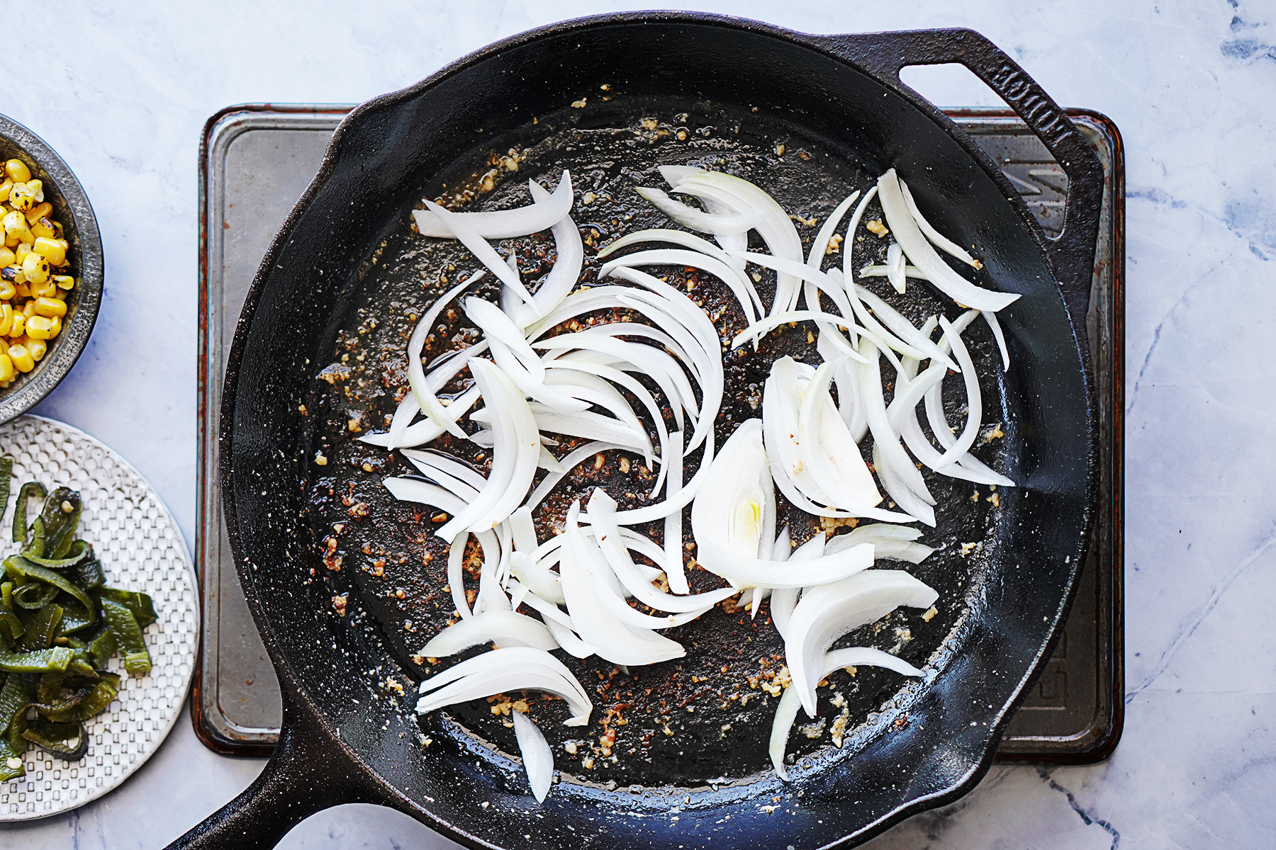 A cast iron skillet cooking sliced white onions