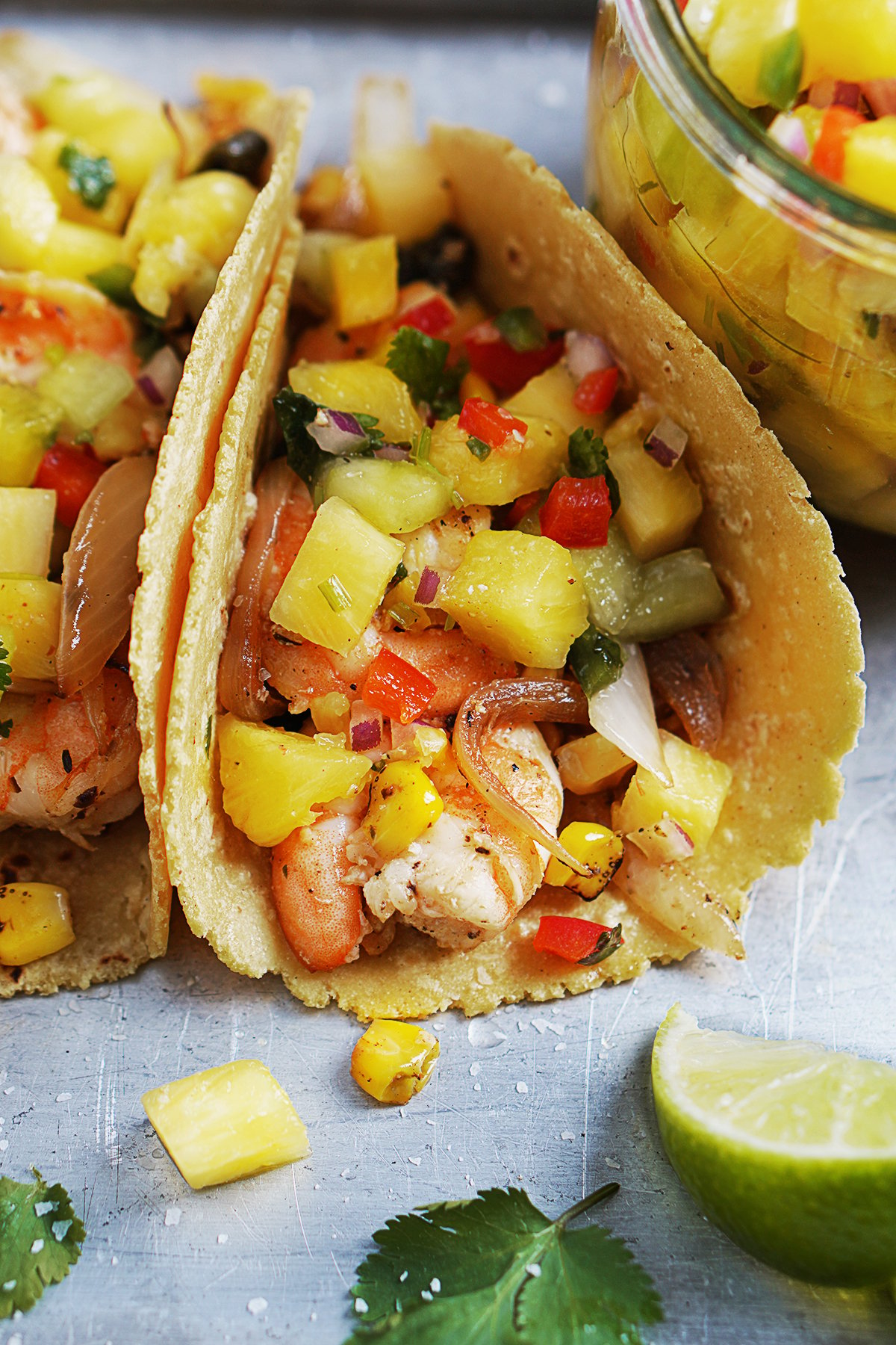 One shrimp taco folded and topped with pineapple salsa