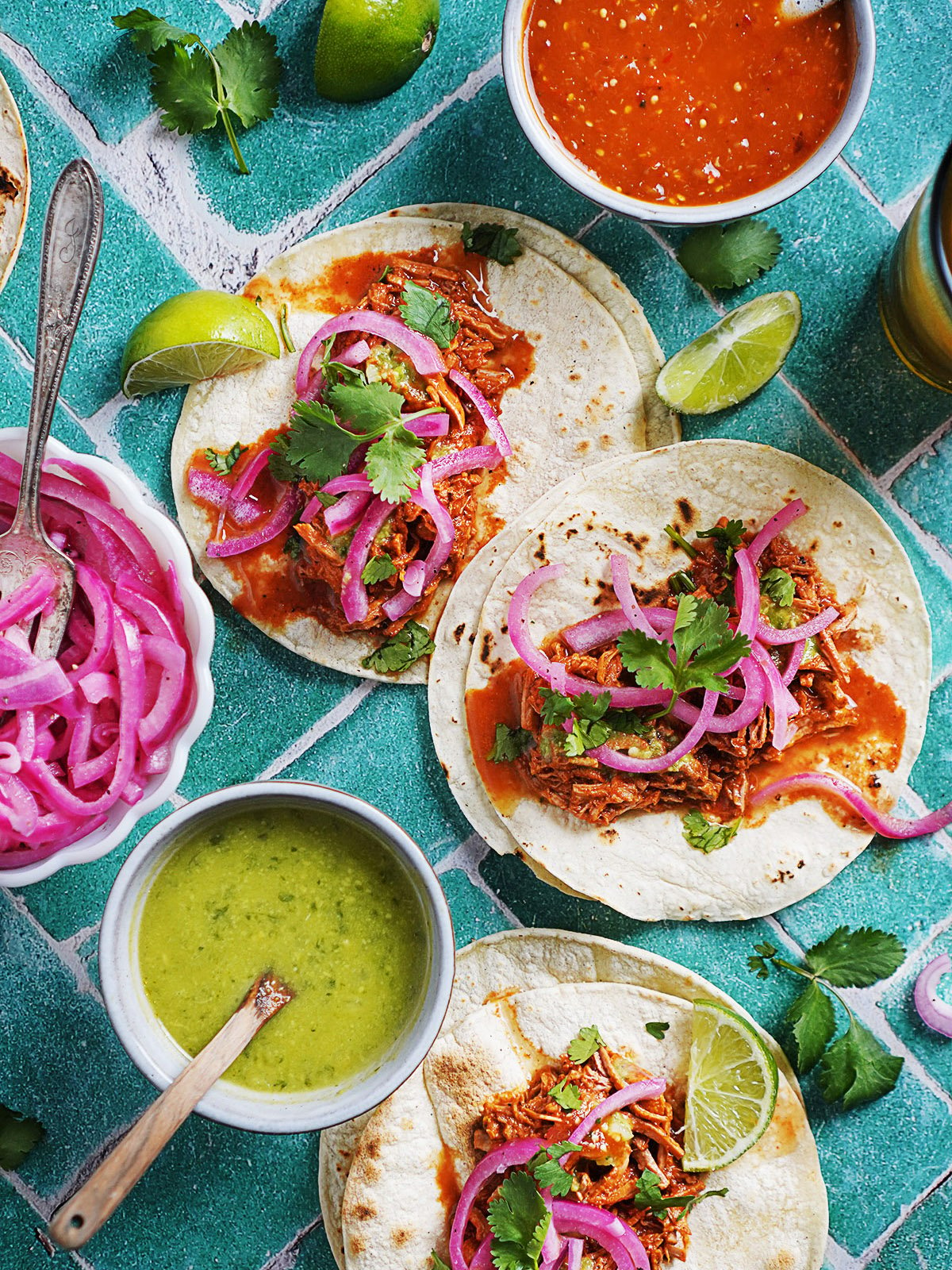 three tacos made with cochinita pibil topped with red pickled onions