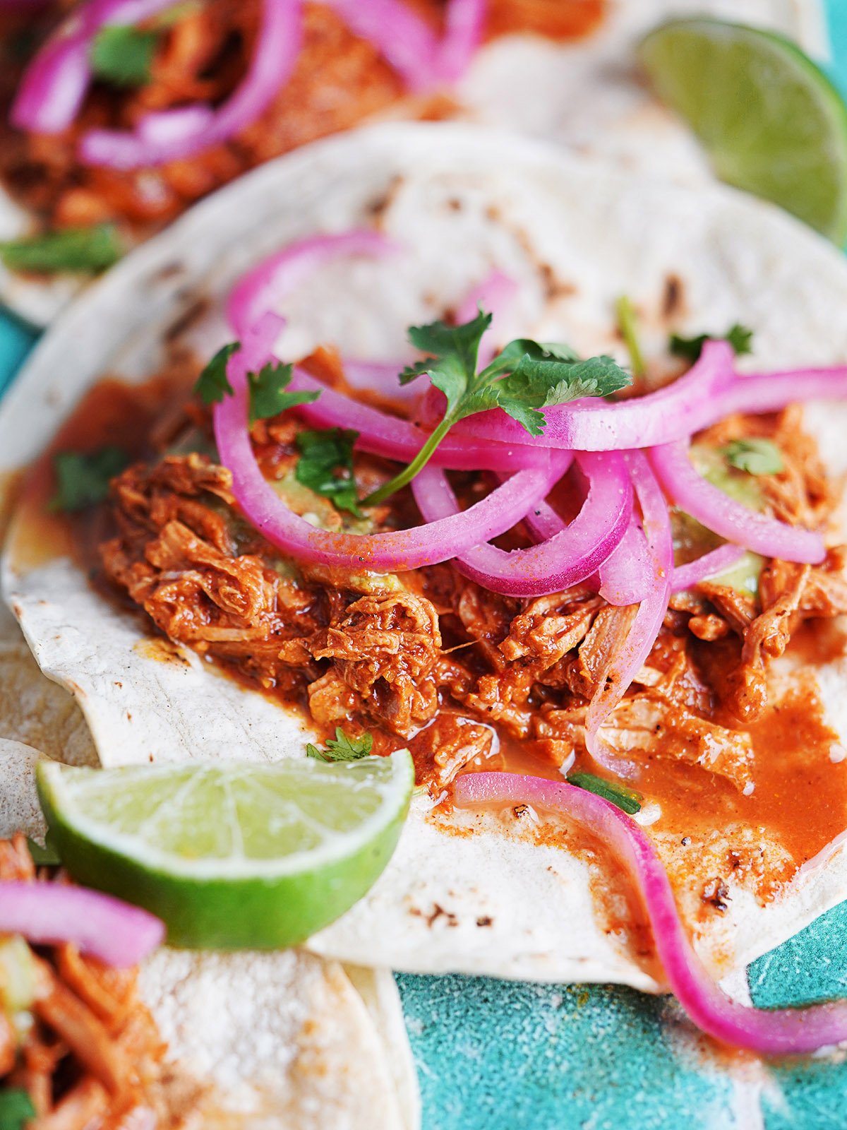 A taco made with cochinita pibil topped with red pickled onions