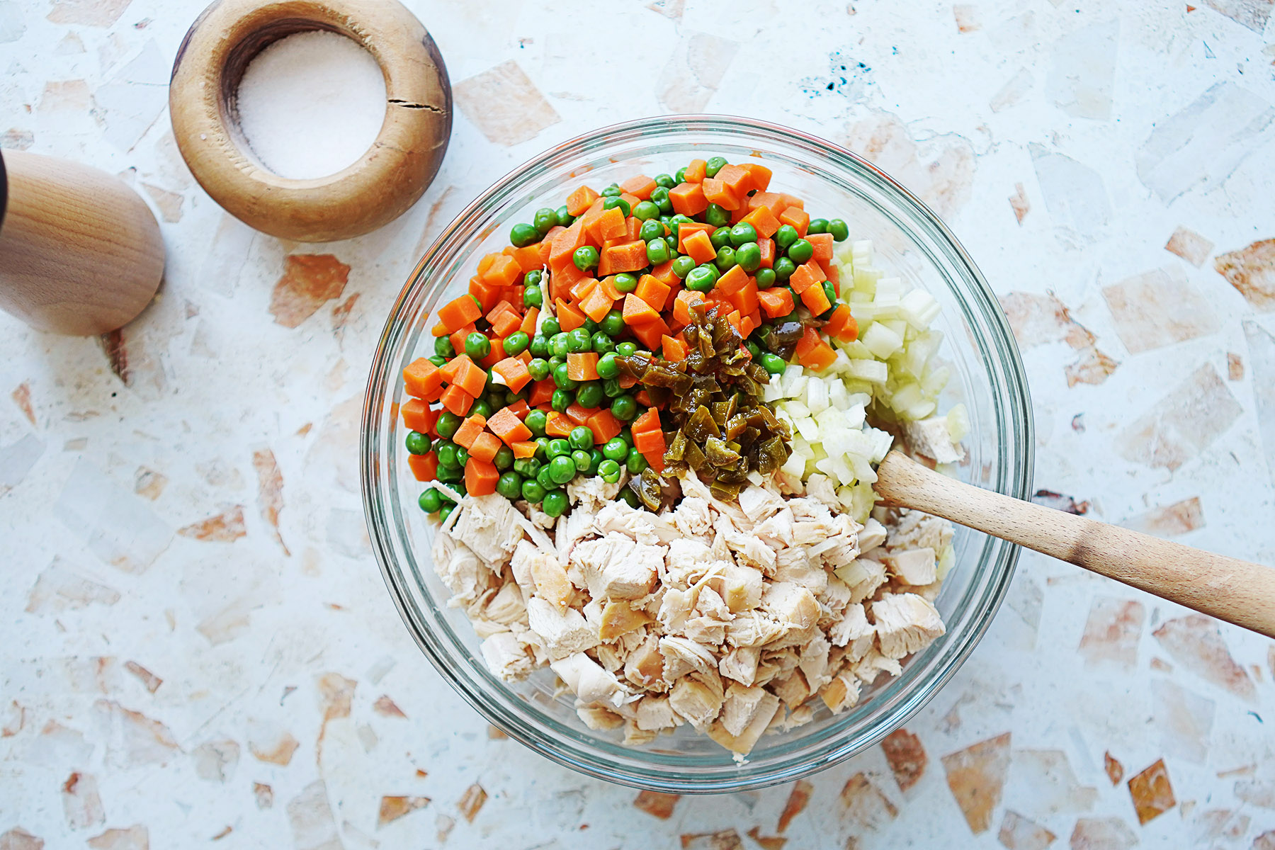 A bowl with cubed chicken, carrots & peas, and celery