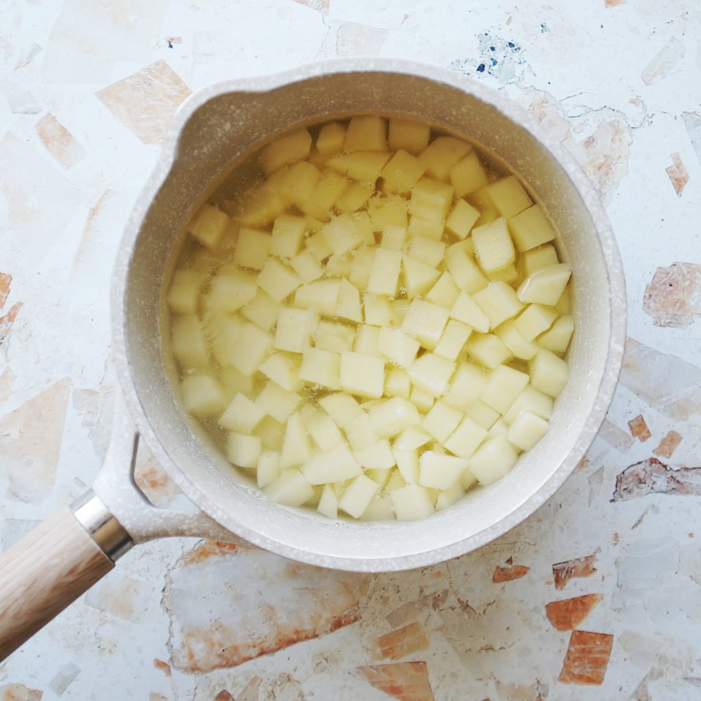 A small saucepan with cubed potatoes covered in water