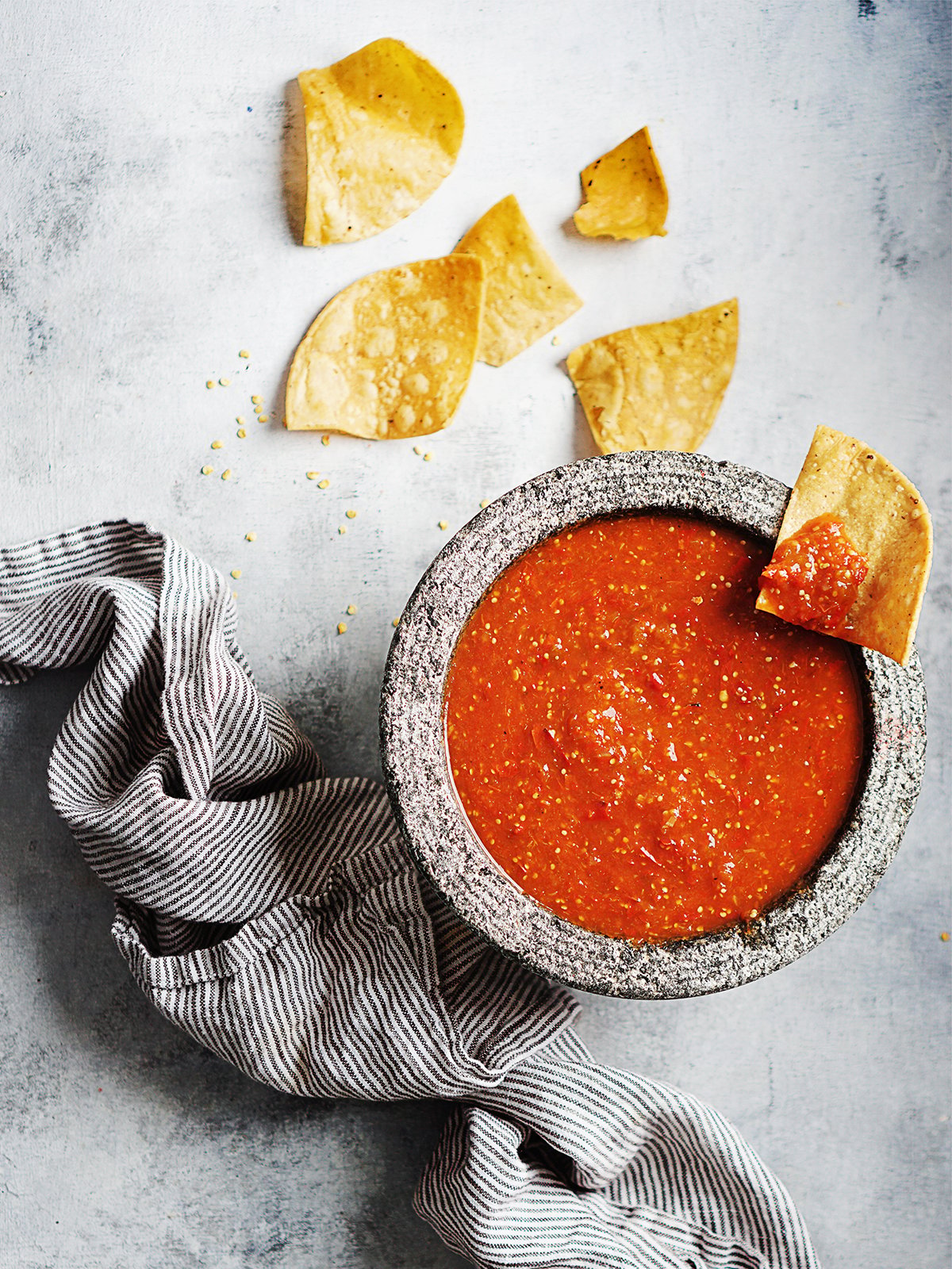 Chile De Arbol Salsa in a molcajete with a gray kitchen towel on the side