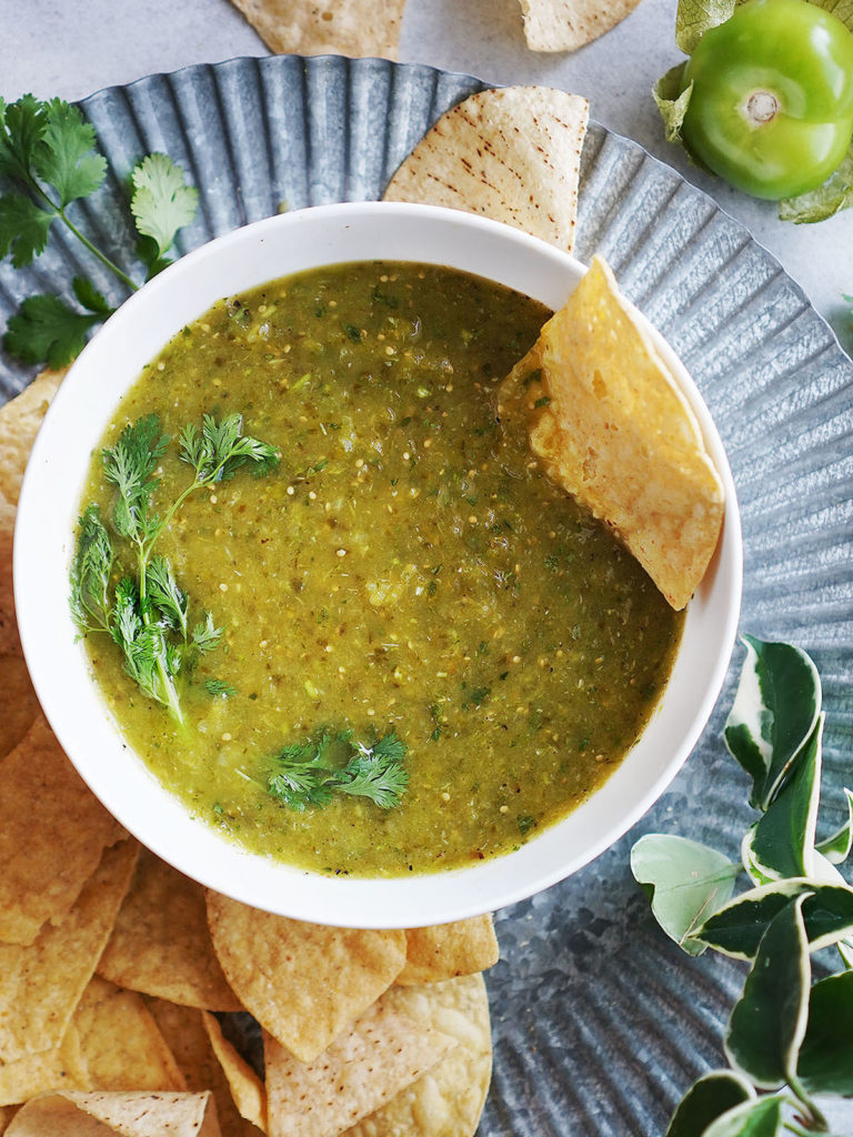 green salsa in a white bowl with tortilla chips on the side