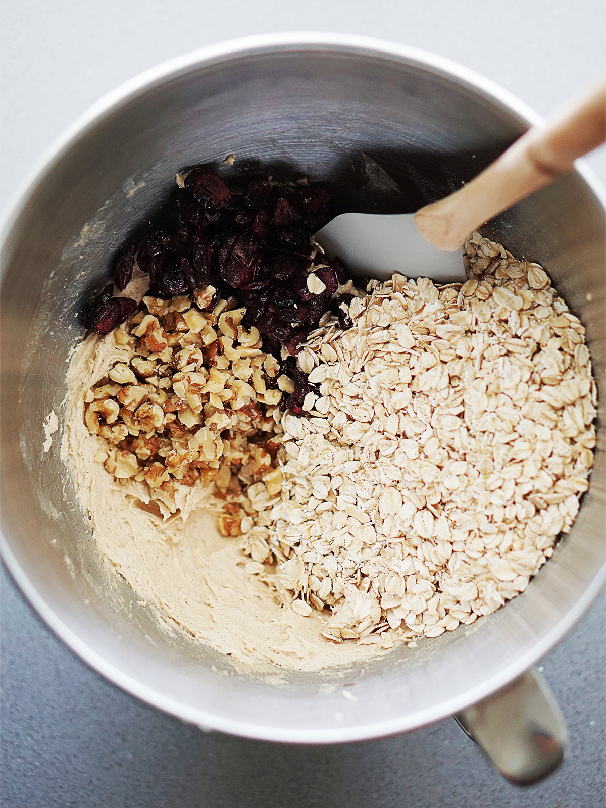 Mixing bowl with cookie dough, oatmeal flakes and chopped walnuts