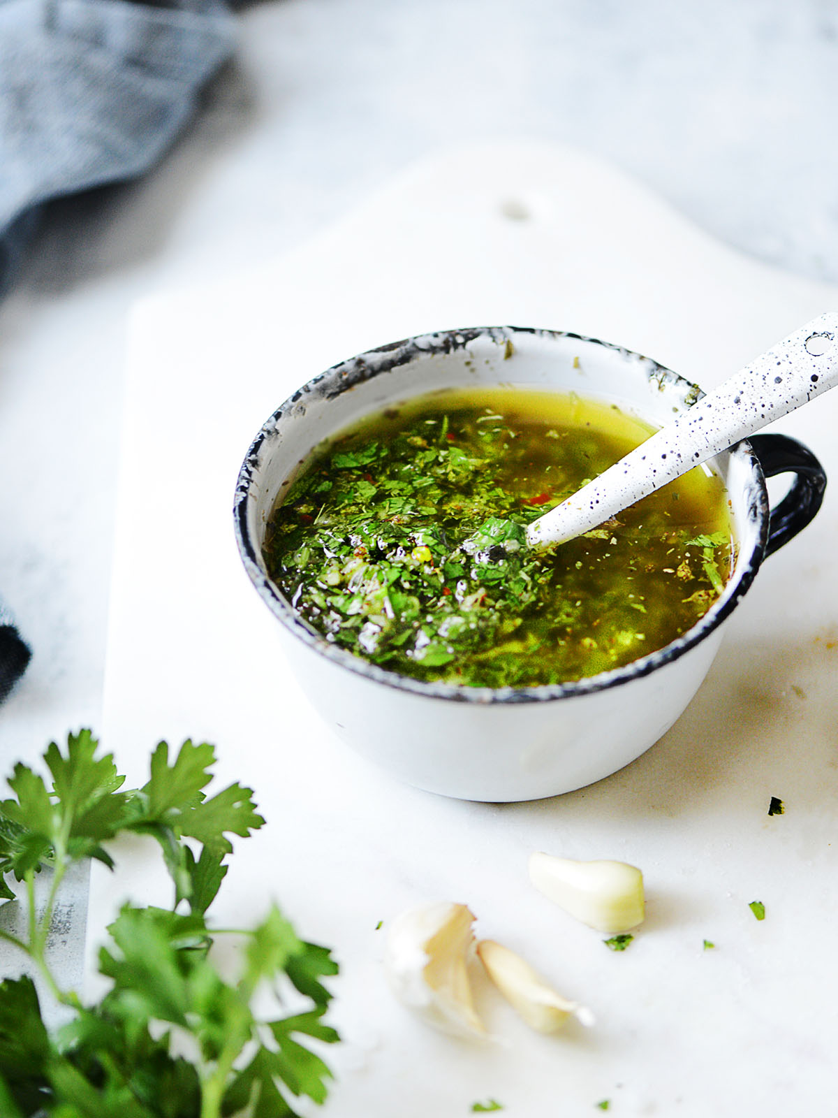 A cup with chimichurri and a white spoon