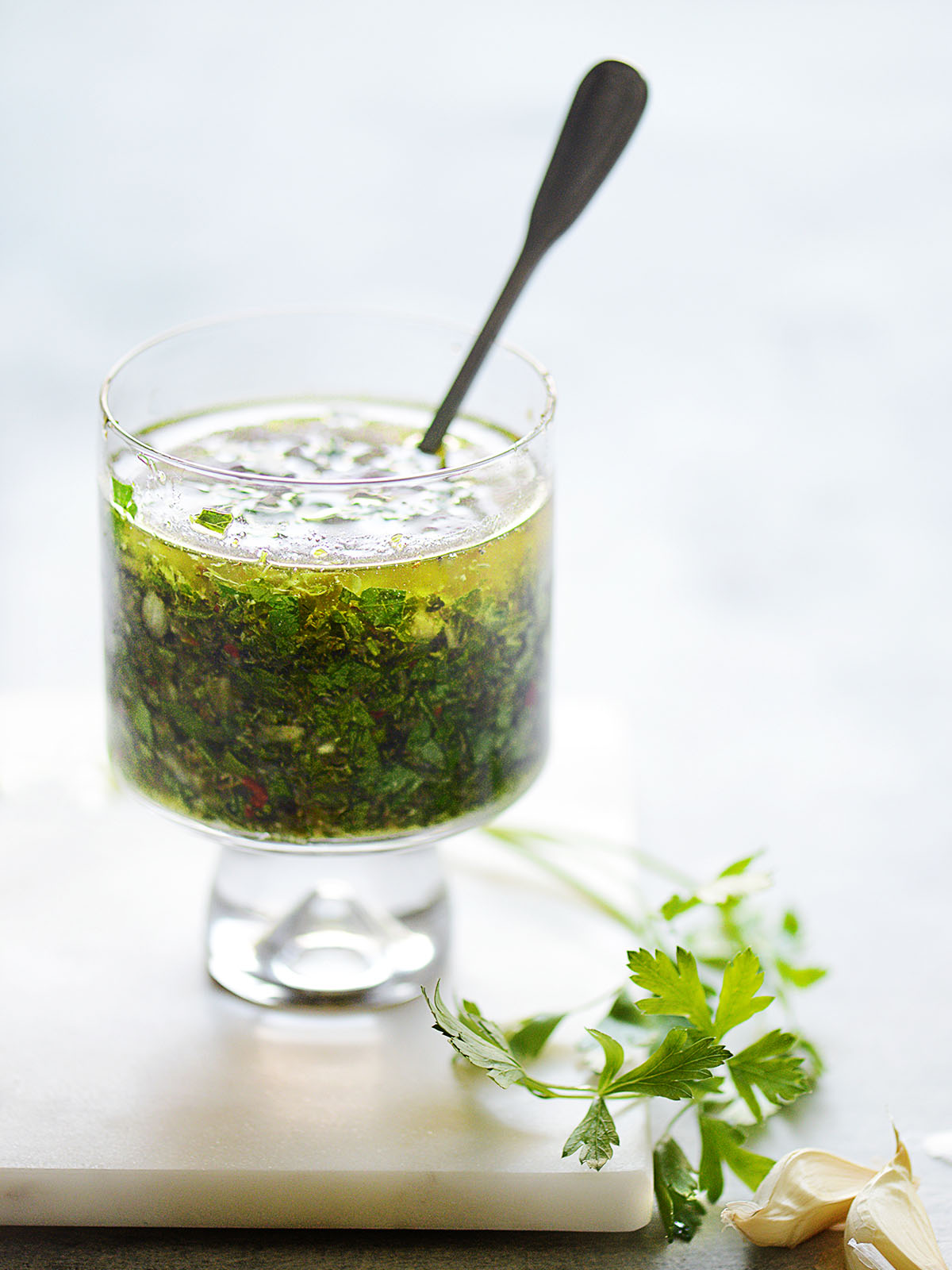 A small glass with chimichurri and parsley on the side
