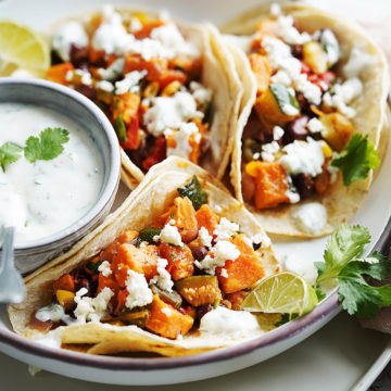 3 vegetable tacos on a white plate garnished with queso fresco