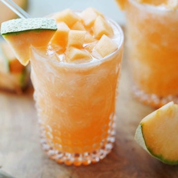 A glass with melon water and chunks on top of the glass.