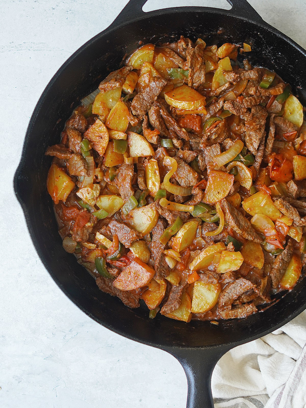 A skillet with cooked steak, potatoes and chiles