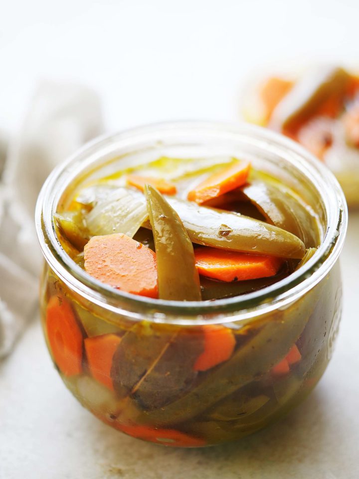 A mix of Jalapeños and carrots in a jar with a vinegar mix.