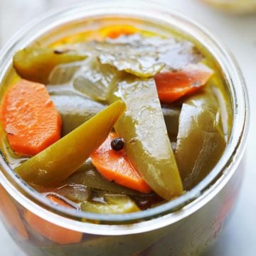 Pickled jalapeños and carrots in a small jar.