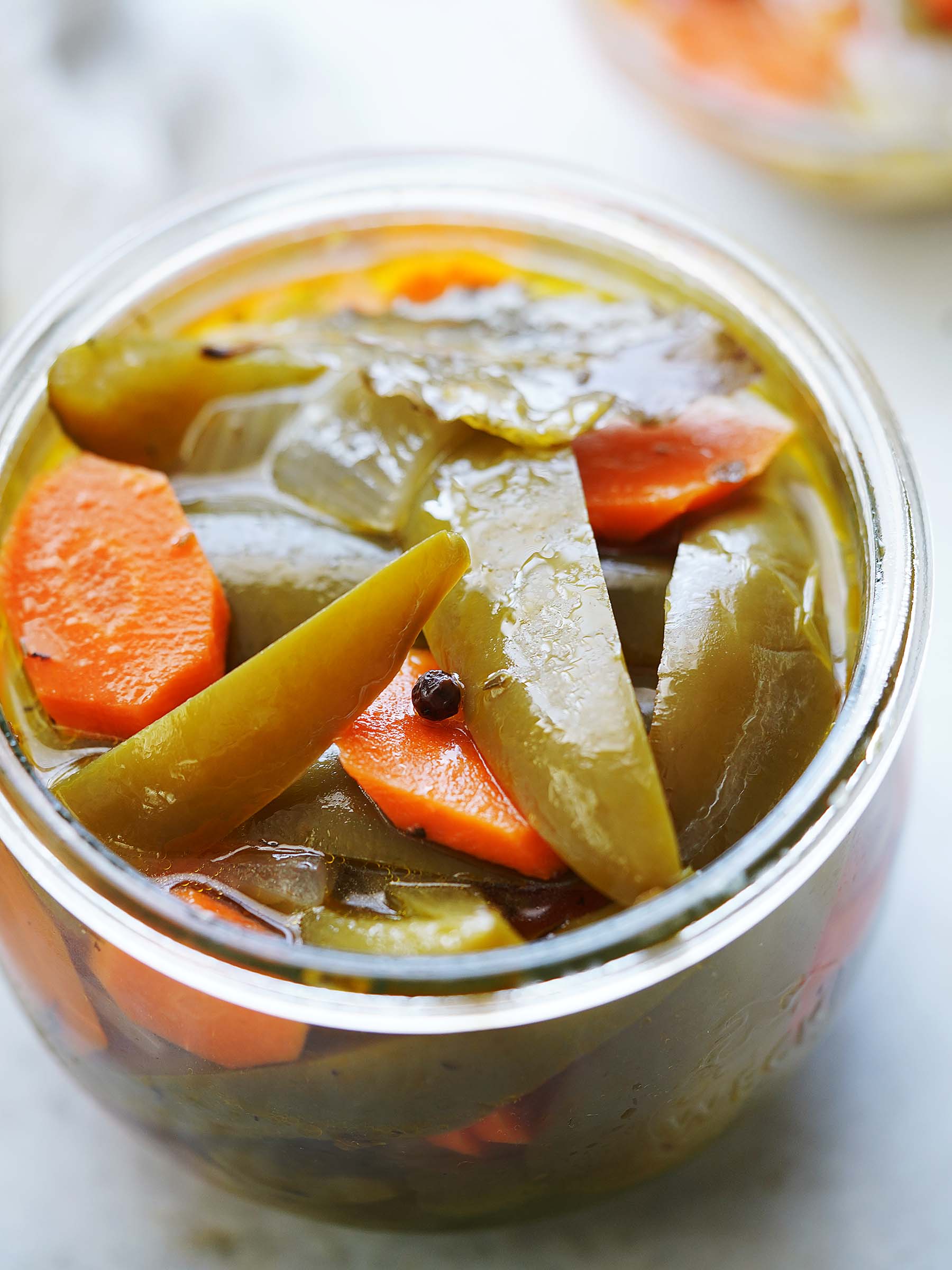 Pickled jalapeños and carrots in a small jar.