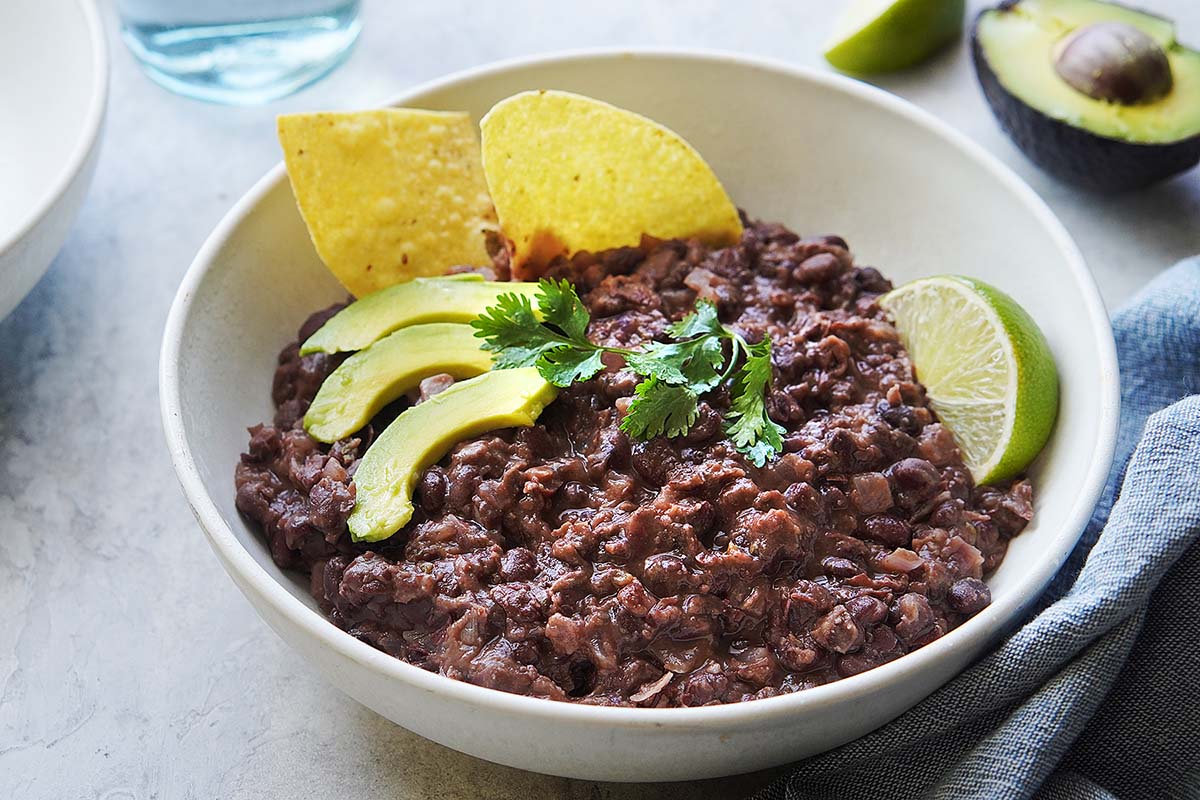 A white bowl with refried black beans.