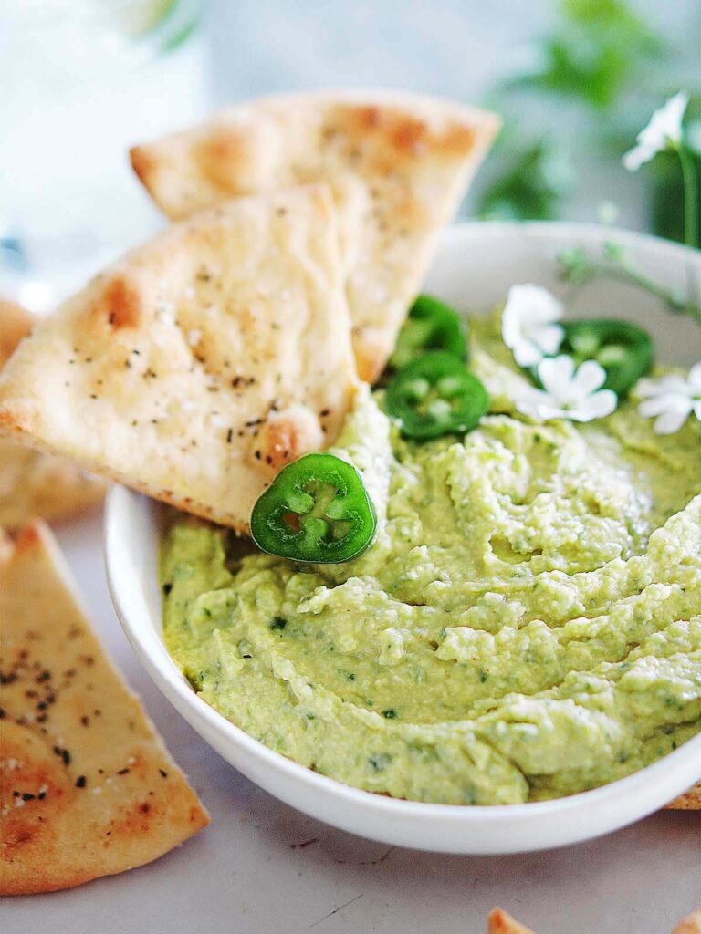 A bowl with Cilantro Jalapeño Hummus and chips on the side.