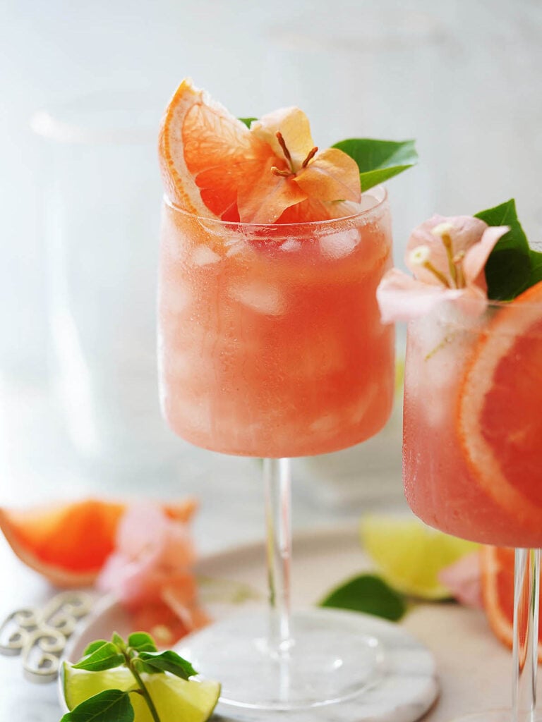 Paloma cocktail garnished with grapefruit and an orange flower.