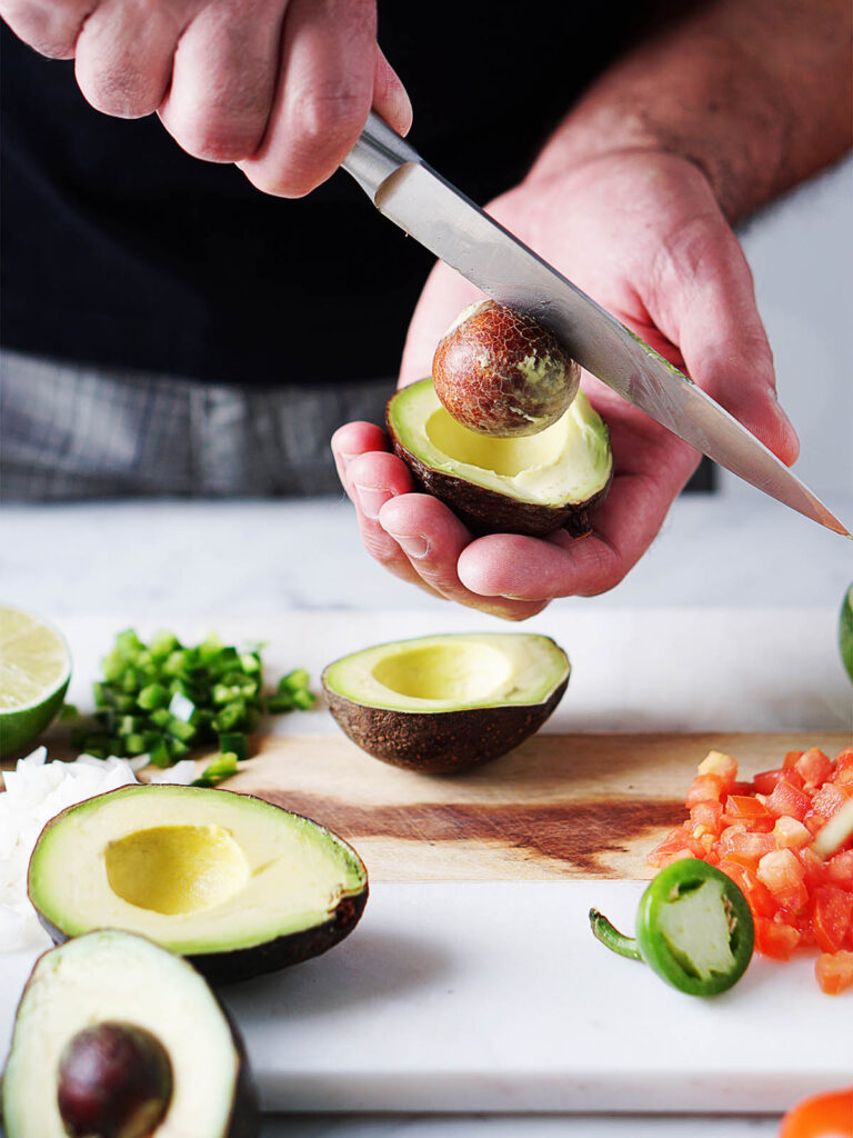 Two hands cutting an avocado.