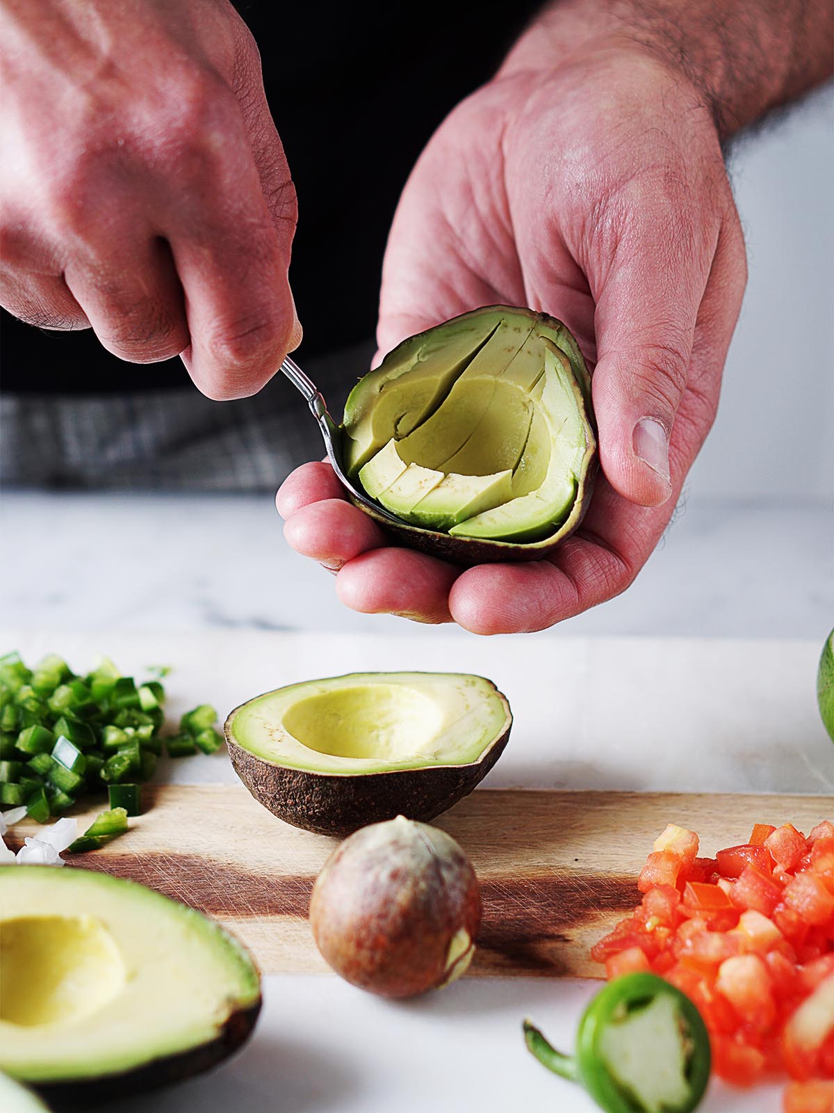 Two hands cutting an avocado.