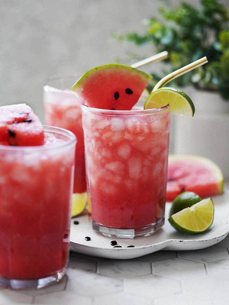 Three glasses with agua de sandia and limes on the side.