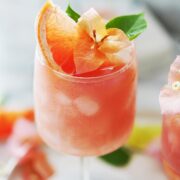 A Paloma cocktail garnished with grapefruit and an orange flower.