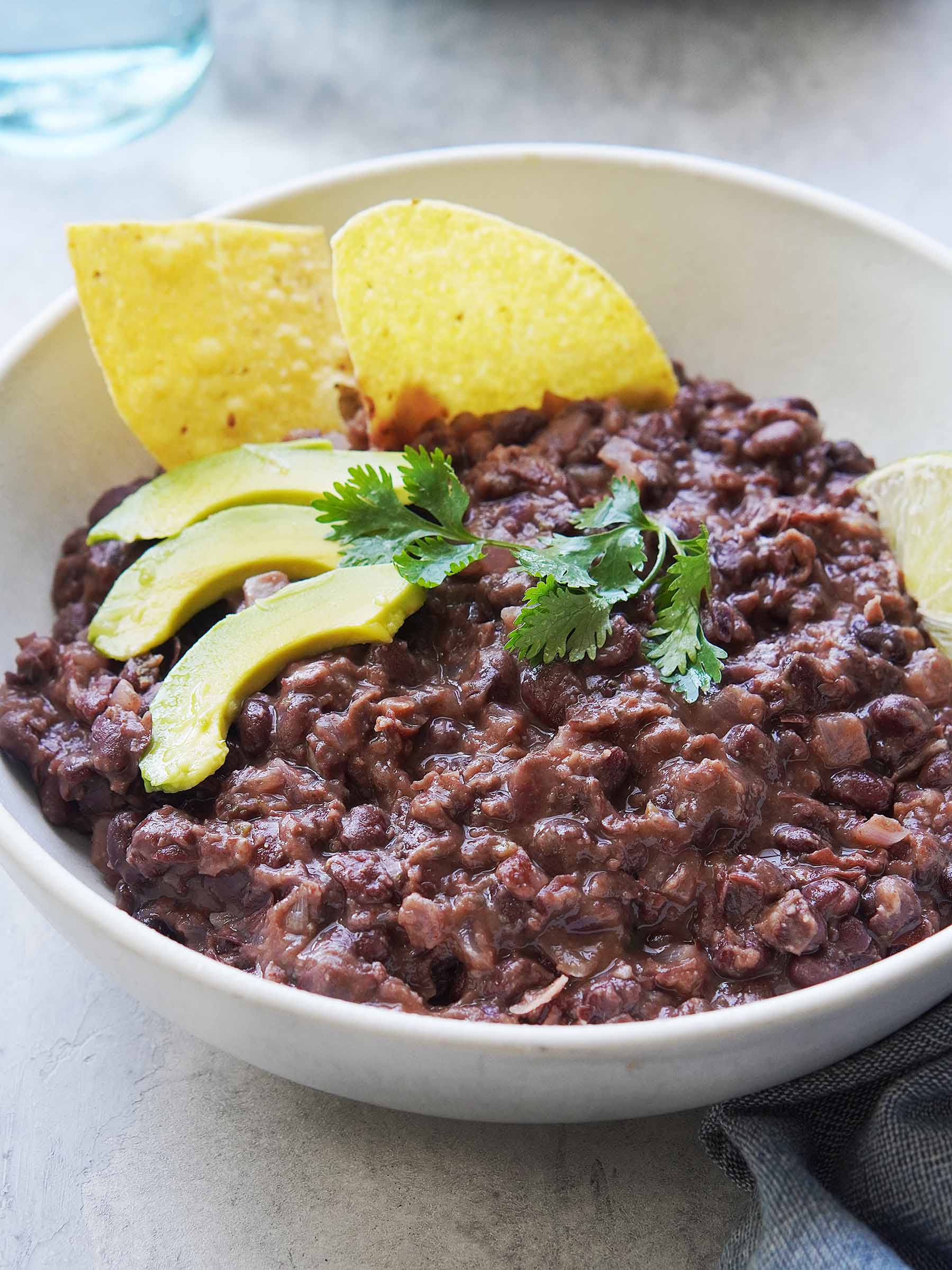 A bowl of black beans with chips on the side