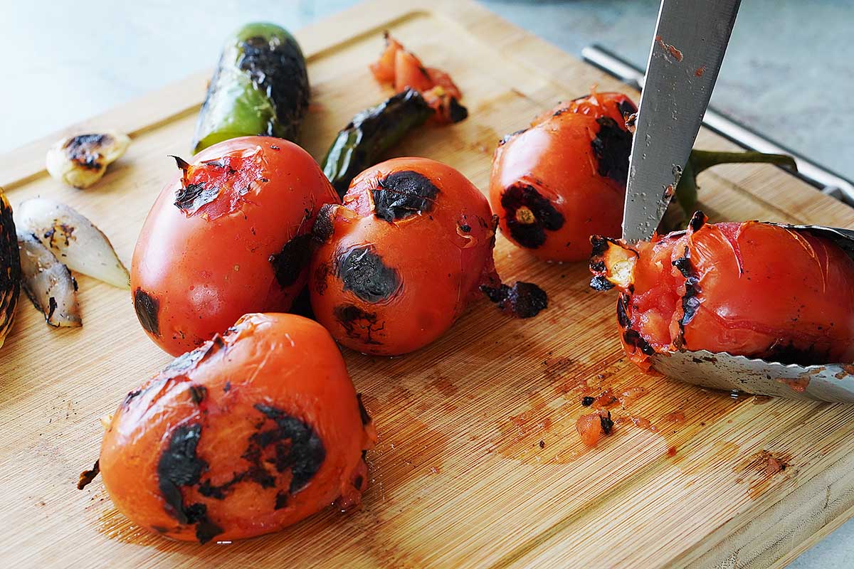 Removing the stem with a knife from toasted tomatoes.