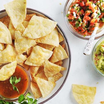 A bowl with baked tortilla chips and salsa on the side.