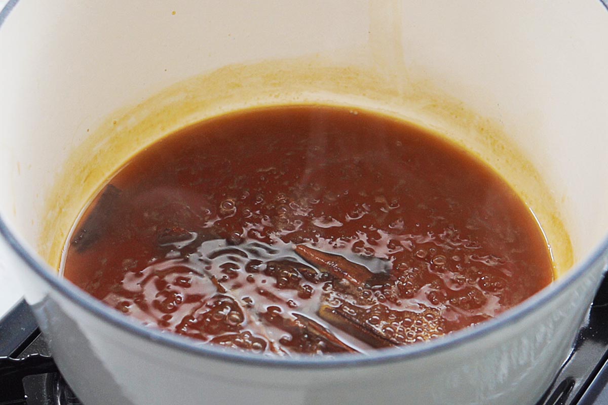 A saucepan with piloncillo, cinnamon stick cooking in water.
