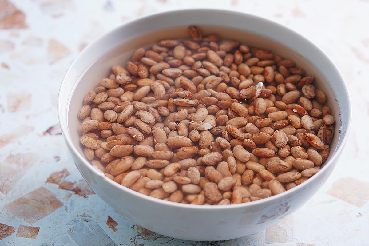 A bowl with beans being soaked in water.