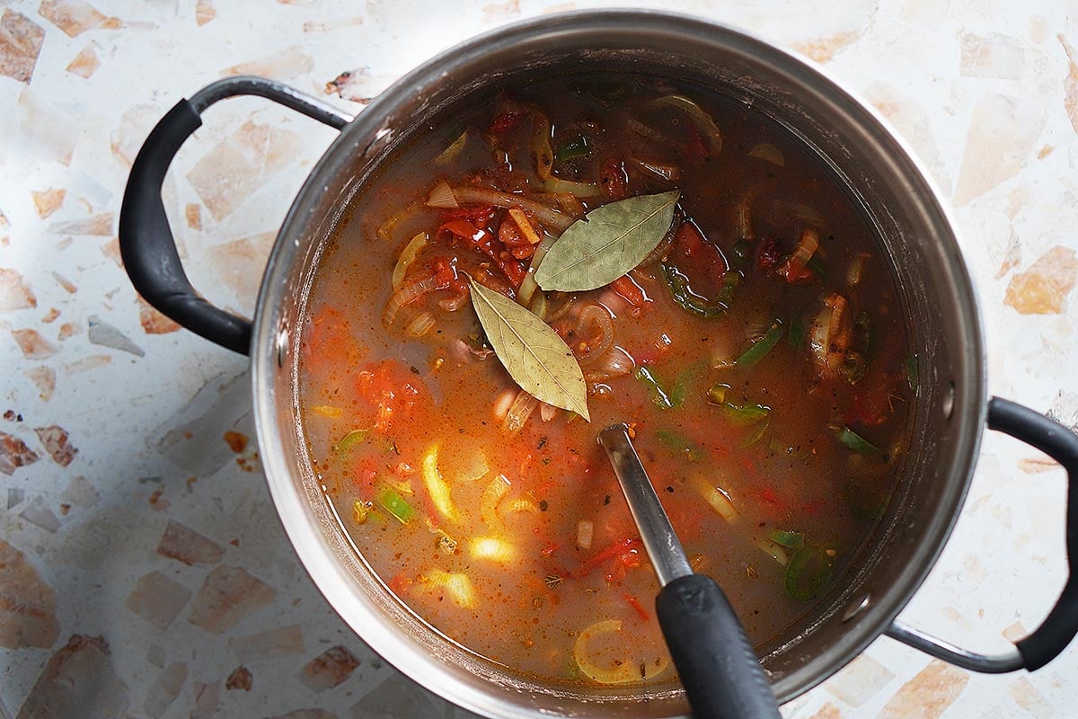 A large pot with cooked pinto beans and vegetables.