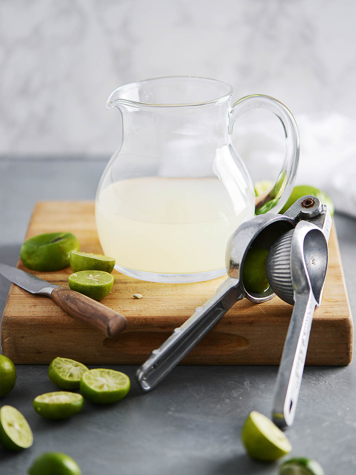 A glass jar half filled with lime juice and squeezed limes on the side.