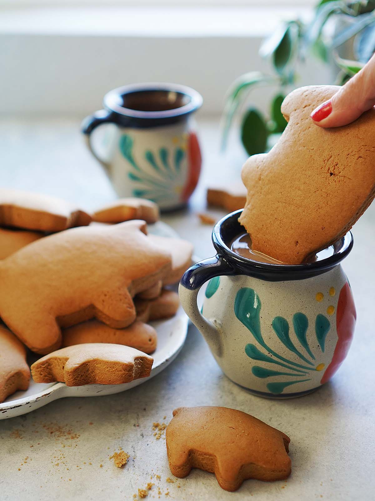 Pig cookies being dipped in a mug with coffee.