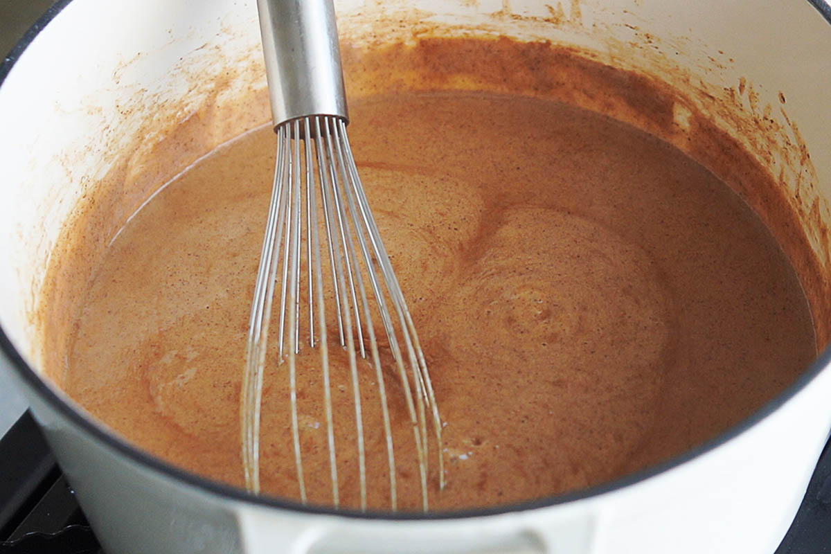A saucepan with hot chocolate being whisked.