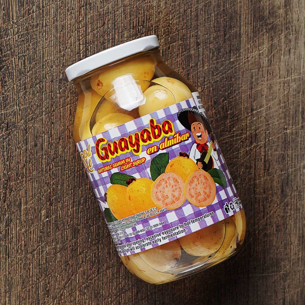 A glass jar with guayabas in syrup.